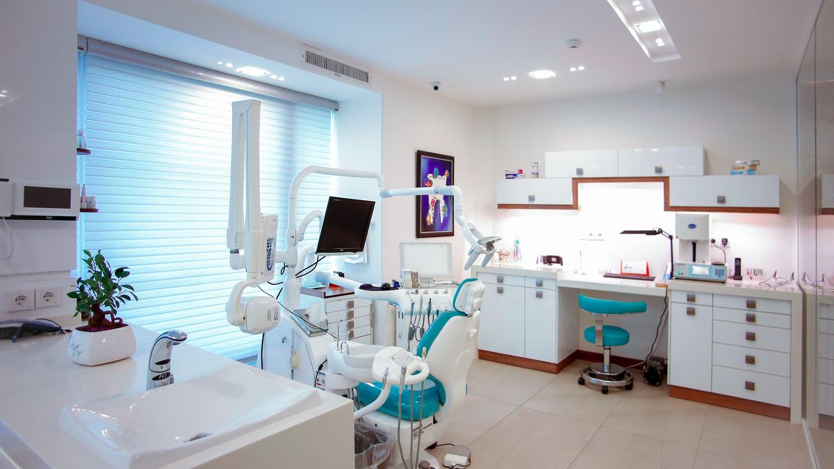 A dental treatment room with a dentist's chair, overhead light, and equipment